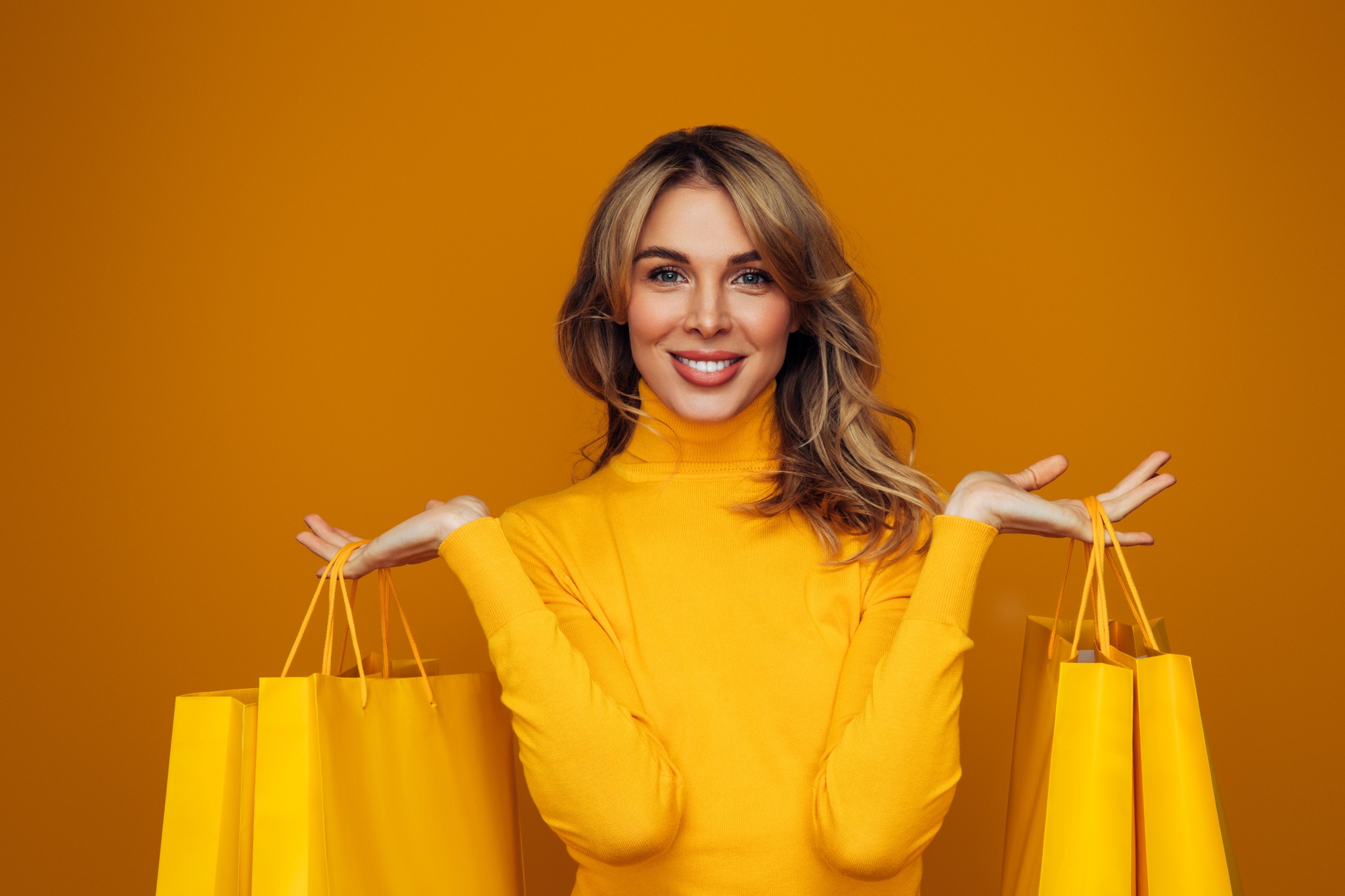 Fall Outdoor Shopping Sale - Blonde women in a yellow long sleeve turtle neck holding yellow shopping bags